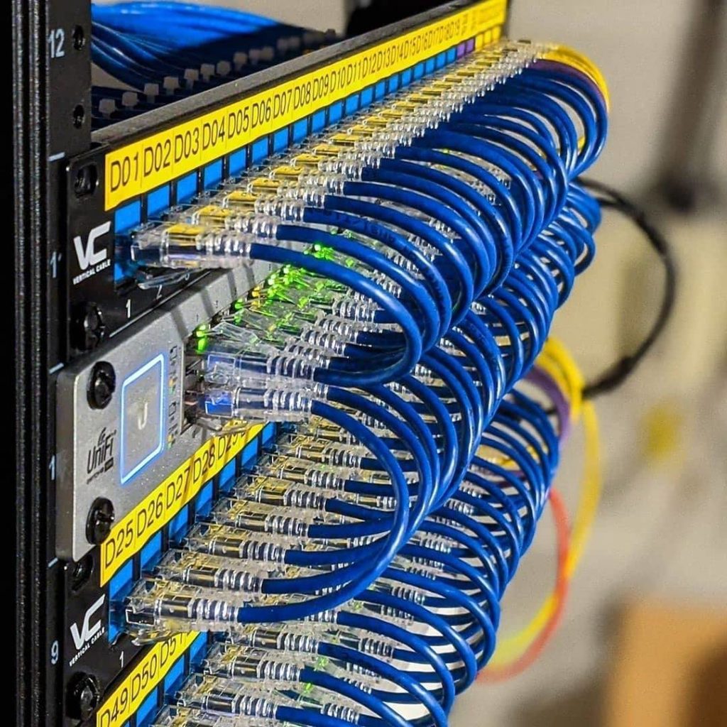Organised blue Ethernet patch leads connected to a network switch and patch panel